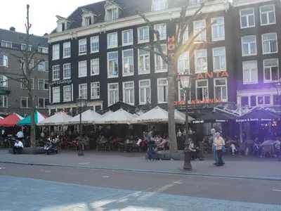 a large building with tables and chairs in front of it at The Blue Stairs in Amsterdam