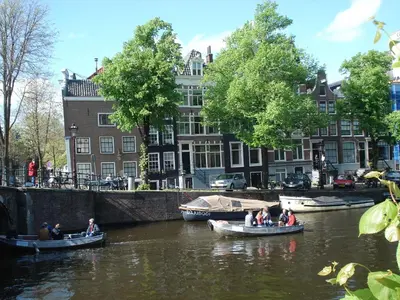 a group of people riding in boats on a river at The Blue Stairs in Amsterdam