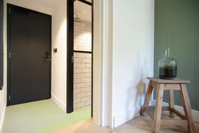 a hallway with a glass vase on a stool next to a door at Authentic Farmhouse - De Vergulden Eenhoorn in Amsterdam