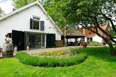 a white house with a flower garden in the yard at Authentic Farmhouse - De Vergulden Eenhoorn in Amsterdam