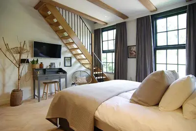 a bedroom with a bed with a desk and a staircase at Authentic Farmhouse - De Vergulden Eenhoorn in Amsterdam