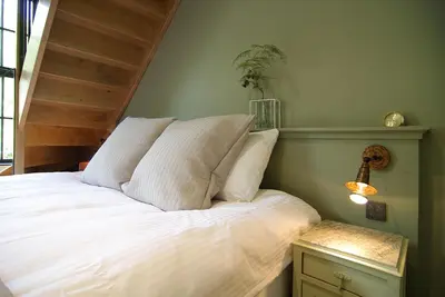 a bedroom with a bed with white sheets and a table at Authentic Farmhouse - De Vergulden Eenhoorn in Amsterdam