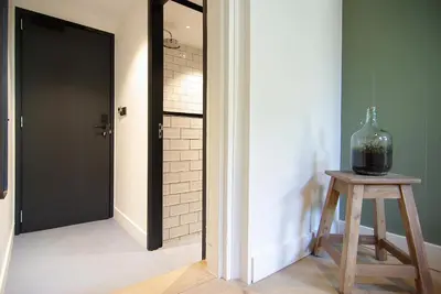 a hallway with a glass vase on a stool next to a door at Authentic Farmhouse - De Vergulden Eenhoorn in Amsterdam