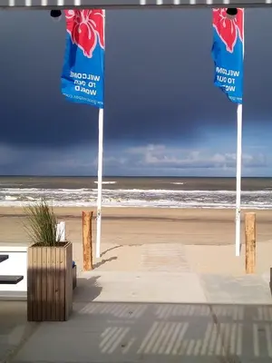 a beach with two blue signs and the ocean at Studio South Beach with garden and free parking in Zandvoort