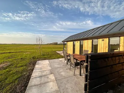 a house with a table and chairs next to a field at Gastenverblijf De Natureluur in Noorden