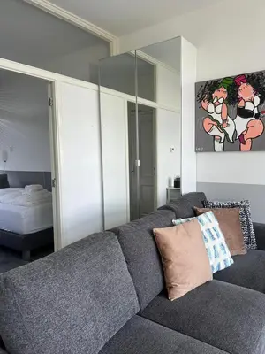 a living room with a gray couch and a bedroom at Dutch Line, De Schelp, Gratis parkeren in Zandvoort