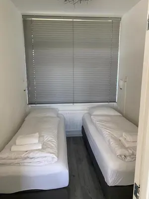 two beds in a room with a window with blinds at Dutch Line, De Schelp, Gratis parkeren in Zandvoort