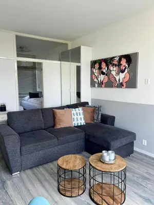 a living room with a blue couch and two tables at Dutch Line, De Schelp, Gratis parkeren in Zandvoort