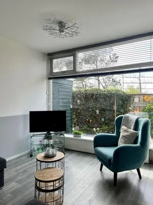 a living room with a blue chair and a tv at Dutch Line, De Schelp, Gratis parkeren in Zandvoort
