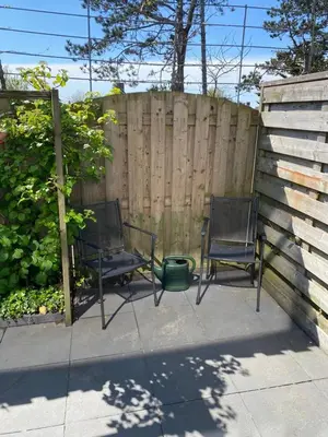 two chairs sitting on a patio next to a fence at Dutch Line, De Schelp, Gratis parkeren in Zandvoort