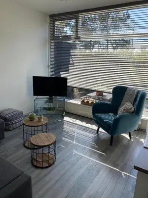 a living room with a blue chair and a television at Dutch Line, De Schelp, Gratis parkeren in Zandvoort