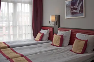 two beds in a hotel room with red and white pillows at Hotel Allure in Amsterdam
