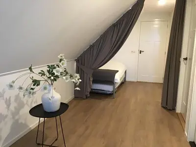 a small room with a bed and a table with flowers at Chez Marly in Oosterblokker