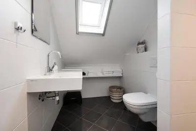 a white bathroom with a toilet and a sink at Chez Marly in Oosterblokker