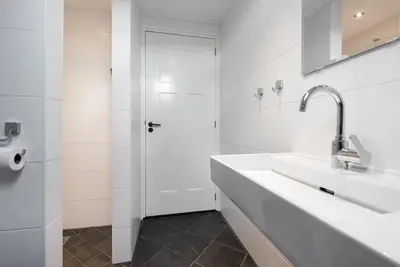 a white bathroom with two sinks and a white door at Chez Marly in Oosterblokker