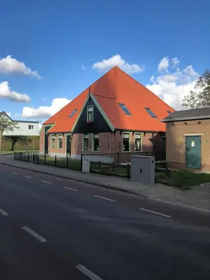 a house with an orange roof on the side of the road at Chez Marly in Oosterblokker