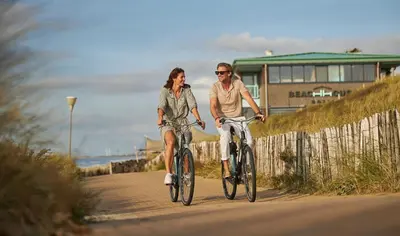 a man and woman riding bikes down a road at Beachhouse Hotel in Zandvoort