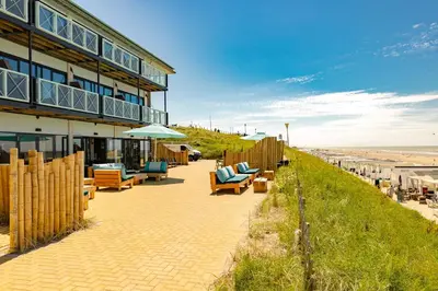 a building with chairs and umbrellas next to the beach at Beachhouse Hotel in Zandvoort