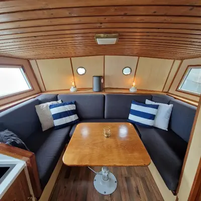 a couch with a table in the back of a boat at City Sailing in Amsterdam