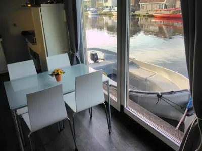 a table and chairs in front of a window with a boat at Boathouse Amsterdam with bikes in Amsterdam