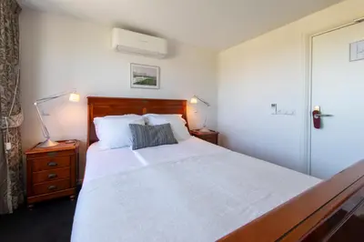 a bedroom with a large white bed with a wooden headboard at Hotel La Rosa Amsterdam Beach in Zandvoort