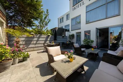 a patio with chairs and tables and a building at Hotel La Rosa Amsterdam Beach in Zandvoort
