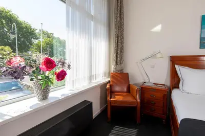 a bedroom with a bed and a window with a vase of flowers at Hotel La Rosa Amsterdam Beach in Zandvoort