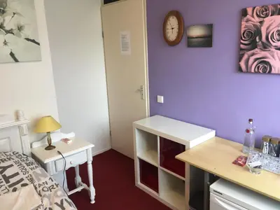 a bedroom with a bed and a desk and a clock at Wim's Place Schiphol Amsterdam Airport in Hoofddorp