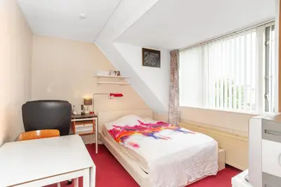 a bedroom with a bed and a chair and a window at Wim's Place Schiphol Amsterdam Airport in Hoofddorp