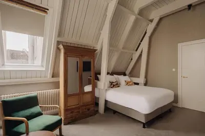 a bedroom with a bed and a chair at Adam's Canal House in Amsterdam