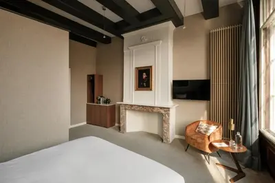 a bedroom with a bed and a chair and a fireplace at Adam's Canal House in Amsterdam