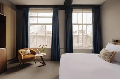 a bedroom with a bed and a chair and window at Adam's Canal House in Amsterdam