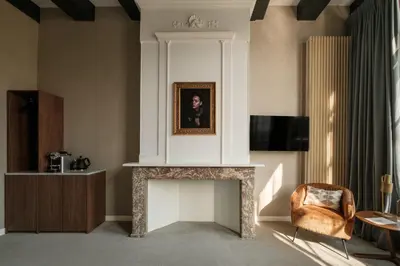 a living room with a fireplace and a chair at Adam's Canal House in Amsterdam