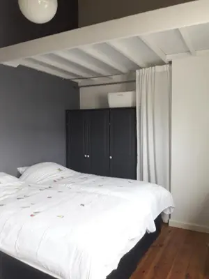 a bedroom with a large bed with white sheets at Vecht & Weide Weesp in Weesp