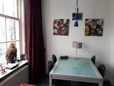 a dining room with a glass table and a window at Jordaan Canal View Apartment in Amsterdam