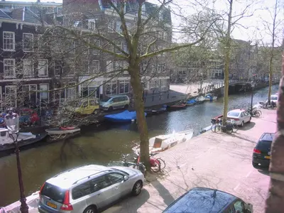 a street with cars parked next to a river at Jordaan Canal View Apartment in Amsterdam