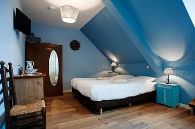 a bedroom with blue walls and a bed with white sheets at De Sfeerstal in Nieuwveen