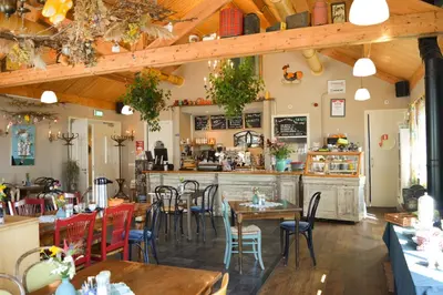 a restaurant with wooden ceilings and tables and chairs at De Sfeerstal in Nieuwveen