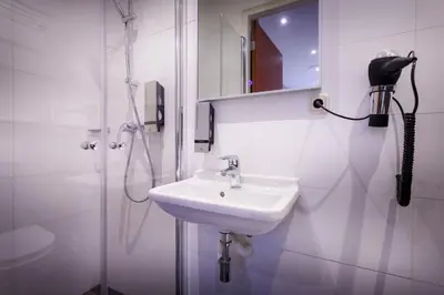 a white bathroom with a shower and a sink at Amsterdam Downtown Hotel in Amsterdam