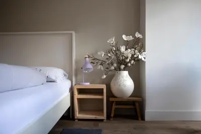 a white vase with flowers on a table next to a bed at Family House Amsterdam in Amsterdam