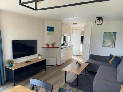 a living room with a couch and a flat screen tv at Blauwe Zeedistel in IJmuiden