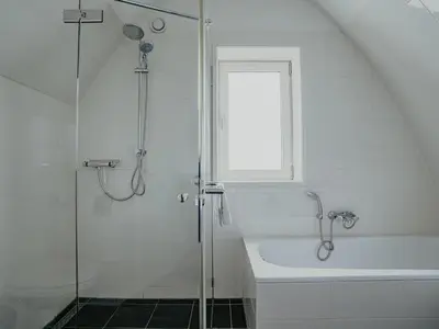 a white bathroom with a shower and a bath tub at Apartment in Egmond with Stunning Sea Views in Egmond aan Zee