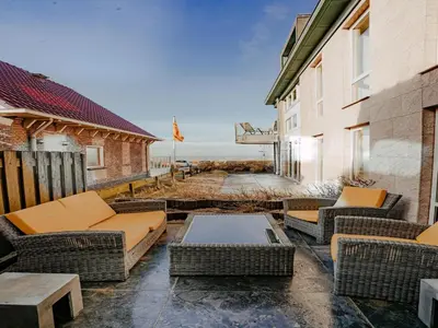 a patio with couches and a coffee table on a building at Apartment in Egmond with Stunning Sea Views in Egmond aan Zee