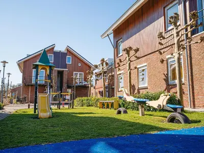 a playground in a yard next to a building at Apartment in Egmond with Stunning Sea Views in Egmond aan Zee