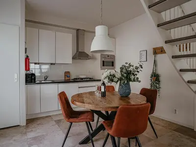 a kitchen with a wooden table with chairs and a vase of flowers at Apartment in Egmond with Stunning Sea Views in Egmond aan Zee