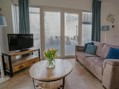 a living room with a couch and a tv and a table at Apartment in Egmond with Stunning Sea Views in Egmond aan Zee