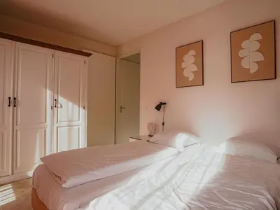 a bedroom with a large white bed and a mirror at Apartment by the Beach with Sea Views in Egmond aan Zee