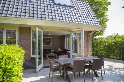 a patio with a table and chairs in front of a house at Holiday Home in Noordwijk with Sunny Garden in Noordwijk aan Zee