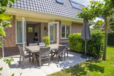 a table and chairs and an umbrella in front of a house at Holiday Home in Noordwijk with Sunny Garden in Noordwijk aan Zee