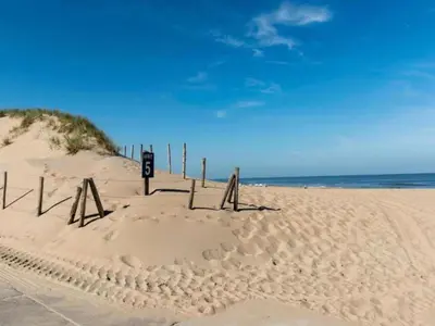 a beach with a sign in the sand at Holiday Home in Noordwijk with Sunny Garden in Noordwijk aan Zee